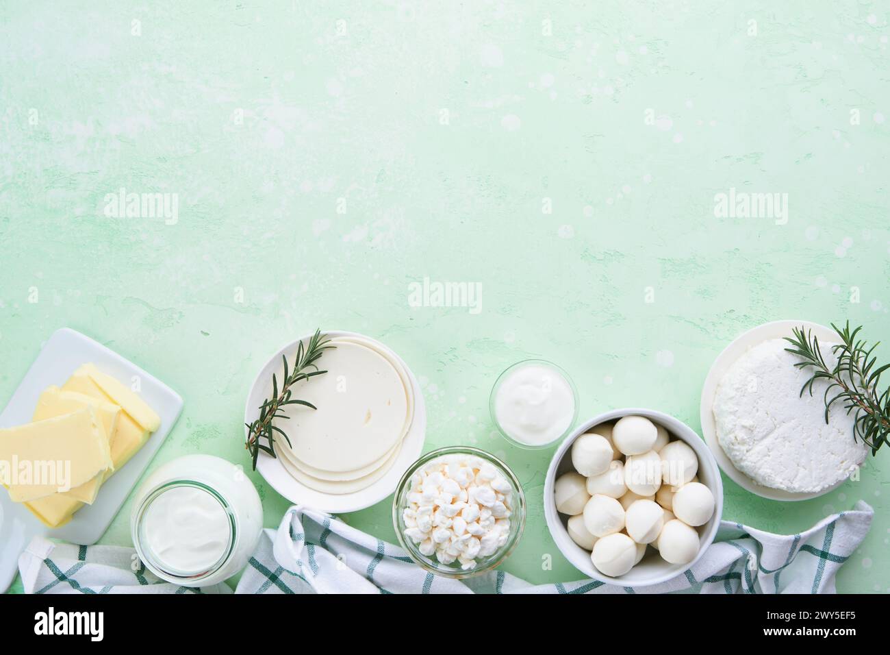 Milcherzeugnisse oder landwirtschaftliche Erzeugnisse. Frische Bio-Milchprodukte Milch, Hüttenkäse, Butter, Sahne, Joghurt, Sauerrahm und Mozzarella auf einem hellgrünen Stockfoto