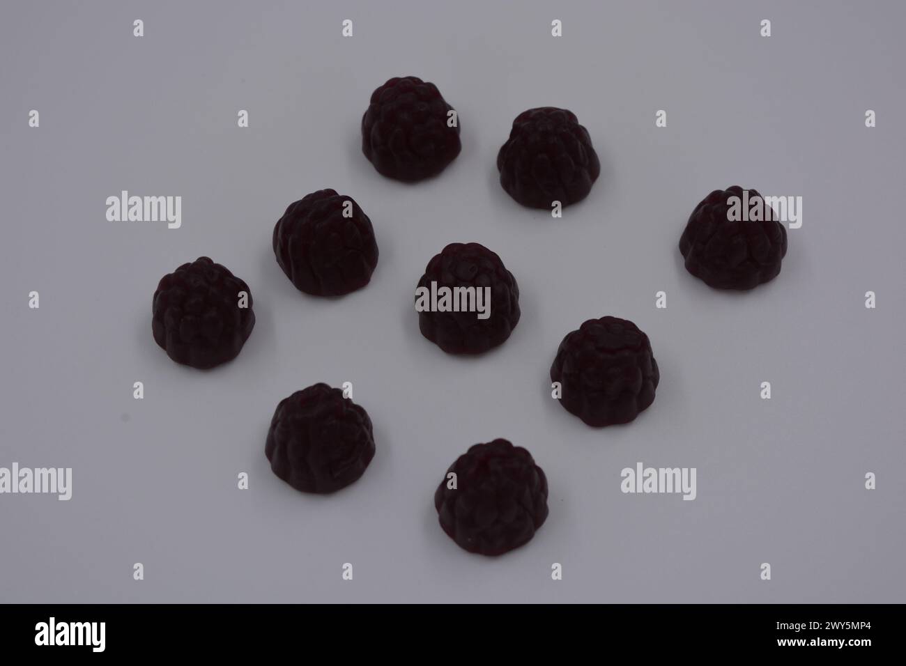 Ungewöhnliche Süßigkeiten, farbige Gelee-Bonbons in Form von Früchten. Schwarze Gelee brombeere und Himbeere sind auf weißem Hintergrund angeordnet. Stockfoto