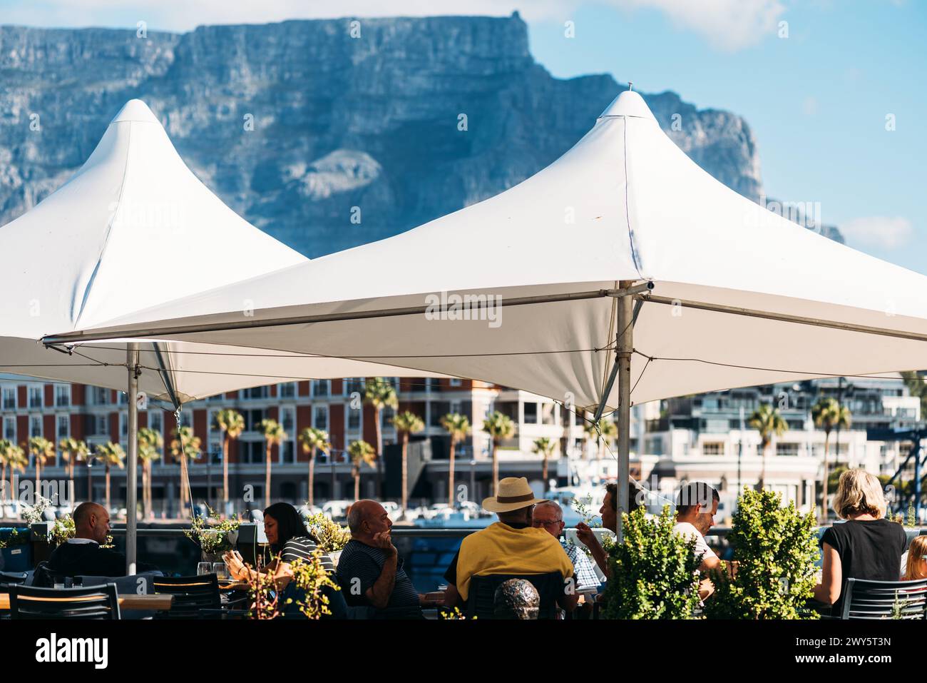 Gäste, die sich in Kapstadts V&A Waterfront mit Blick auf den Tafelberg, Südafrika, entspannen Stockfoto