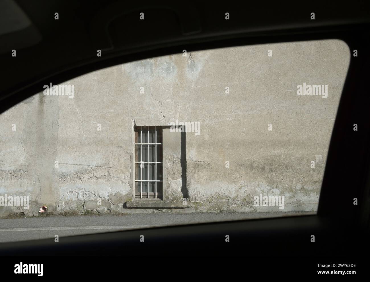 Fenster mit Gittern und Betonwand durch ein Autofenster Stockfoto