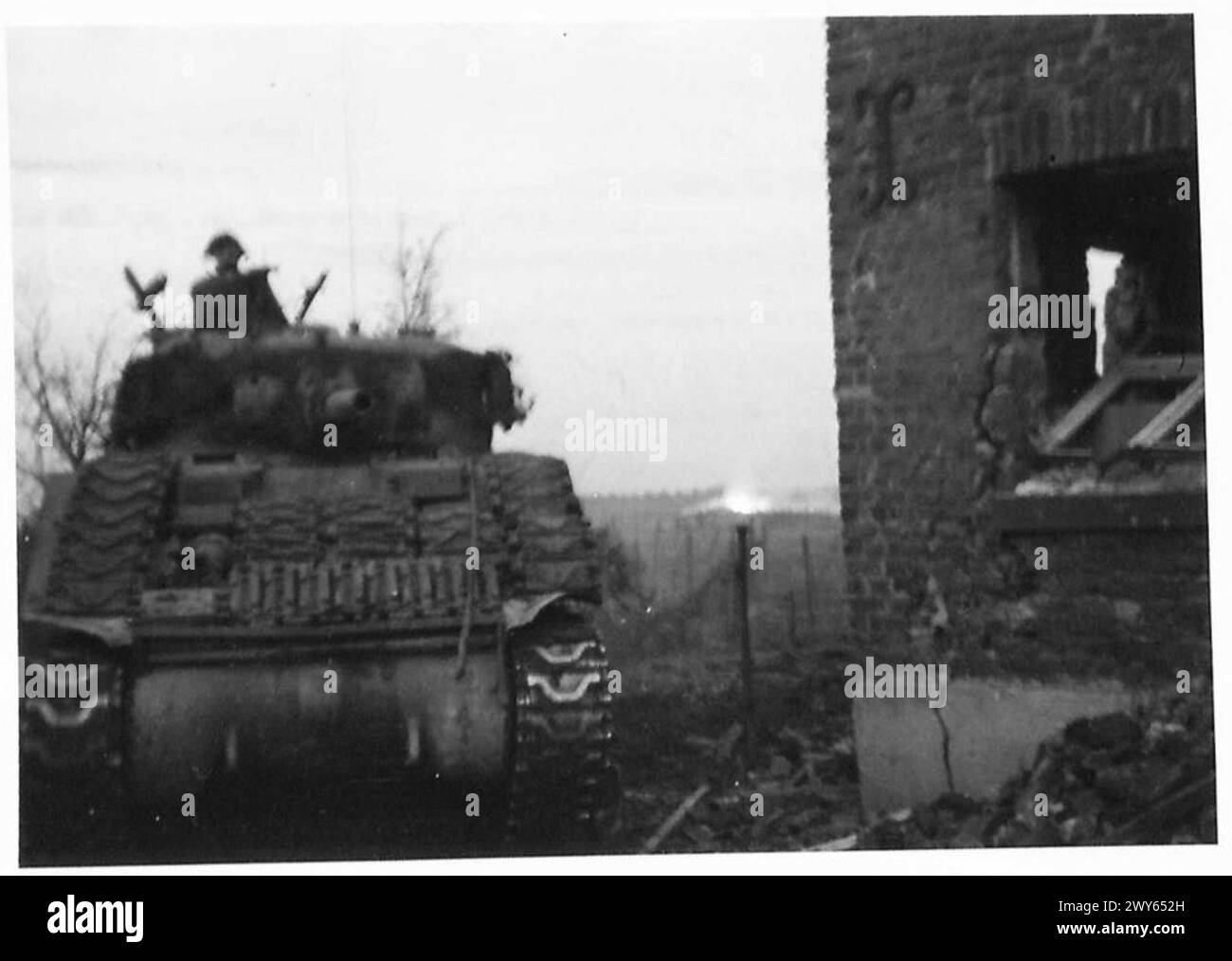 Britische Panzer rücken vor, um die Infanterie während der ersten Schlacht in Deutschland zu unterstützen, wobei rechts ein beschädigter deutscher Stützpunkt zu sehen ist. Stockfoto