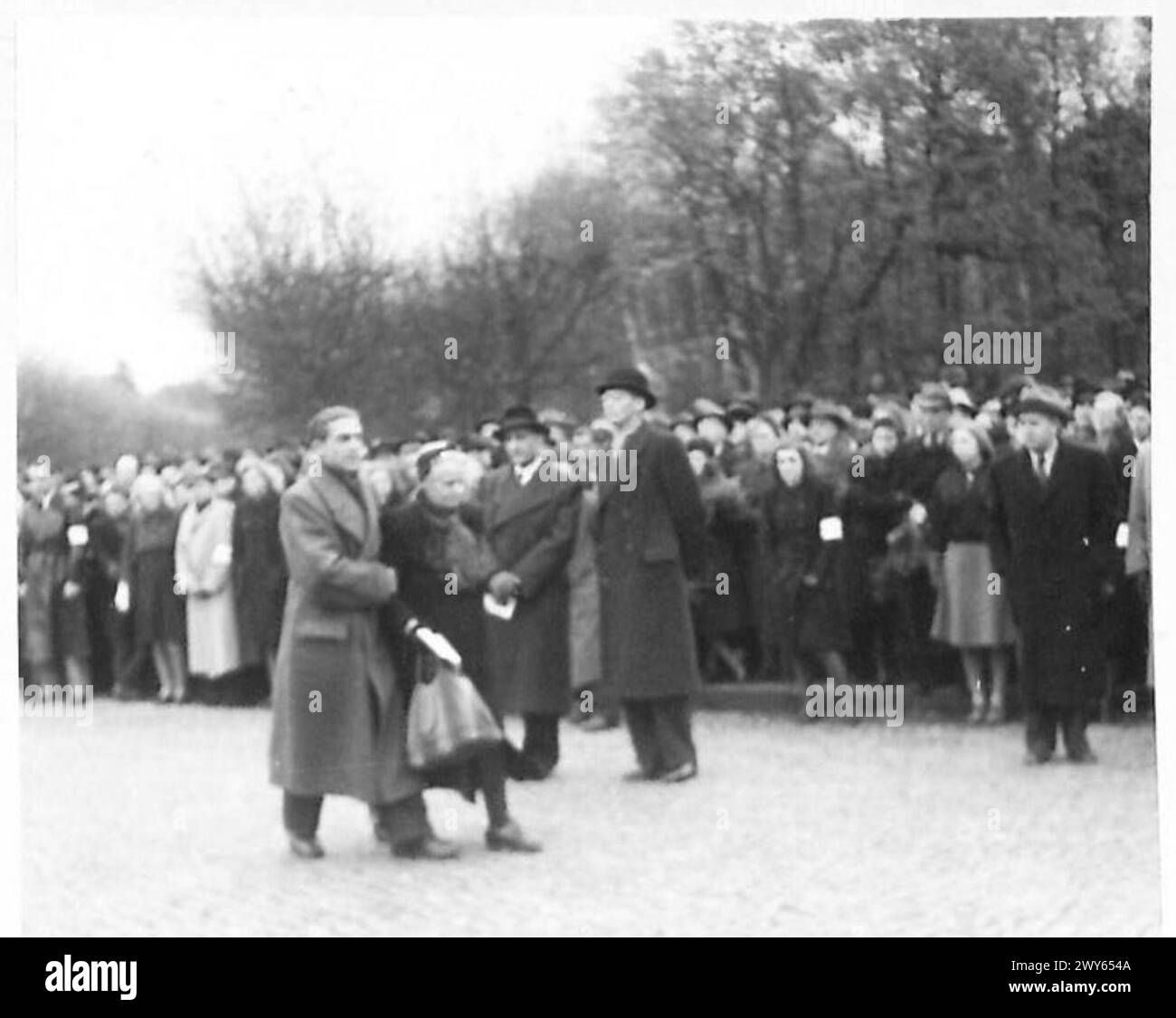 Bei einer deutschen Gedenkfeier wird eine ältere Frau während einer Rede zu Ehren der KZ-Opfer begleitet. Stockfoto