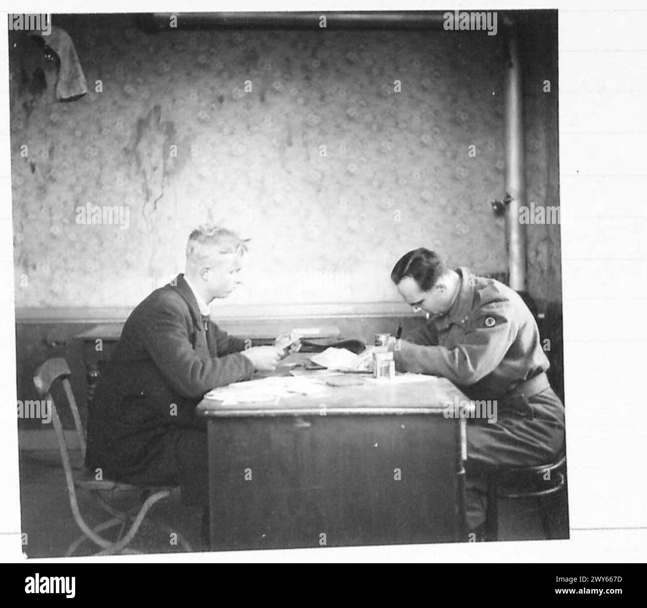 Ein niederländischer Offizier befragt einen jungen deutschen Zivilisten unter der Aufsicht der britischen Armee 21st Army Group während der Operation nach der Befreiung. Stockfoto