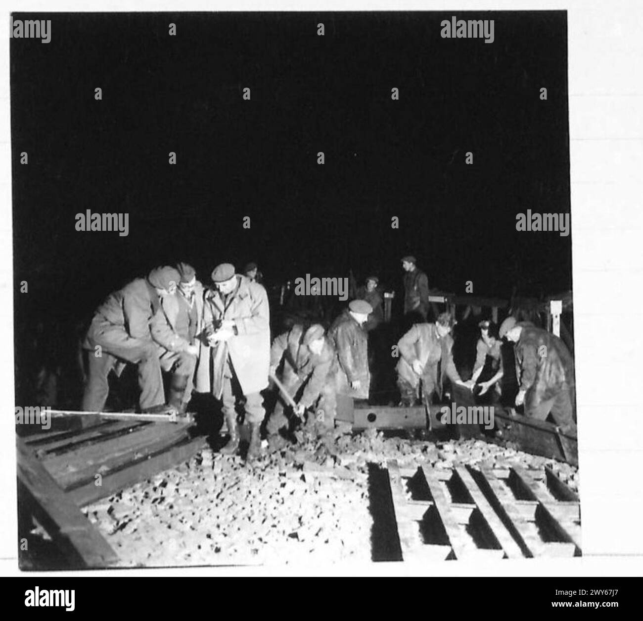 Die Sappers arbeiten nachts mit Riesenhebern, um neue Abschnitte auf der Bailey Bridge zu positionieren, während die Offiziere Pläne überprüfen, die Teil der britischen Armee, 21st Army Group sind. Stockfoto