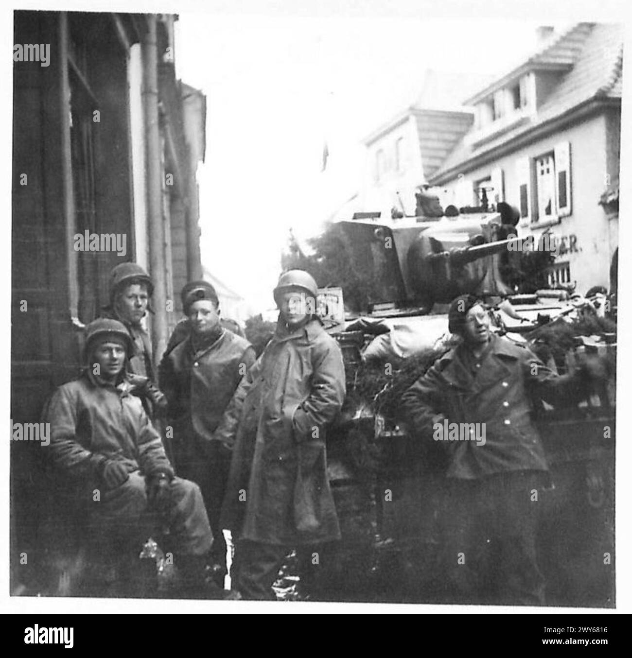 US-AMERIKANISCHE und britische Soldaten grüßen in Issum, während während der Operationen des Zweiten Weltkriegs eine weiße Flagge gehisst wird. Stockfoto
