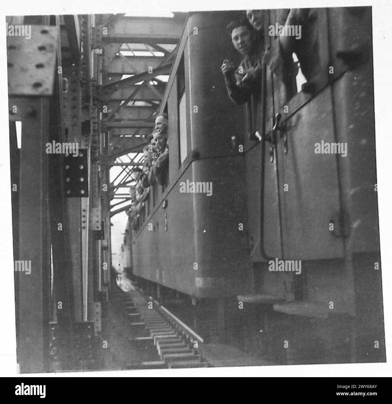 Truppen der Britischen Rheinarmee beobachten die Überquerung der Ijssel bei Deventer von Zugwagen aus, während der Zug über die Brücke fährt. Stockfoto