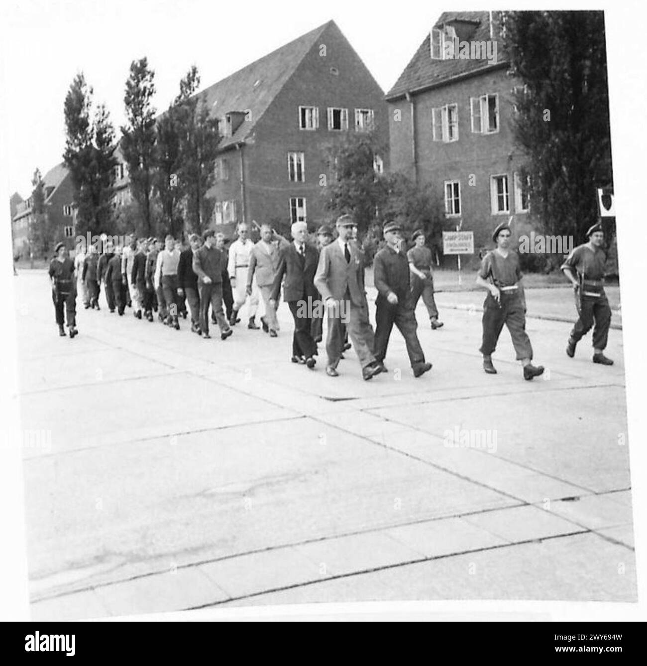 Eine Arbeitsgruppe deutscher politischer Gefangener marschiert unter bewaffneter Bewachung, um im Lager Arbeit zu leisten. Stockfoto