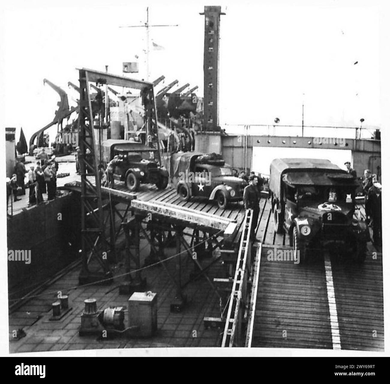 Ein Kraftfahrzeug bewegt sich vom Deck eines Landeschifftanks zu einer Pierhead, wobei eine konstruierte Rampe an einem vorgefertigten Hafen verwendet wird. Die 21. Armeegruppe der britischen Armee ist anwesend. Stockfoto
