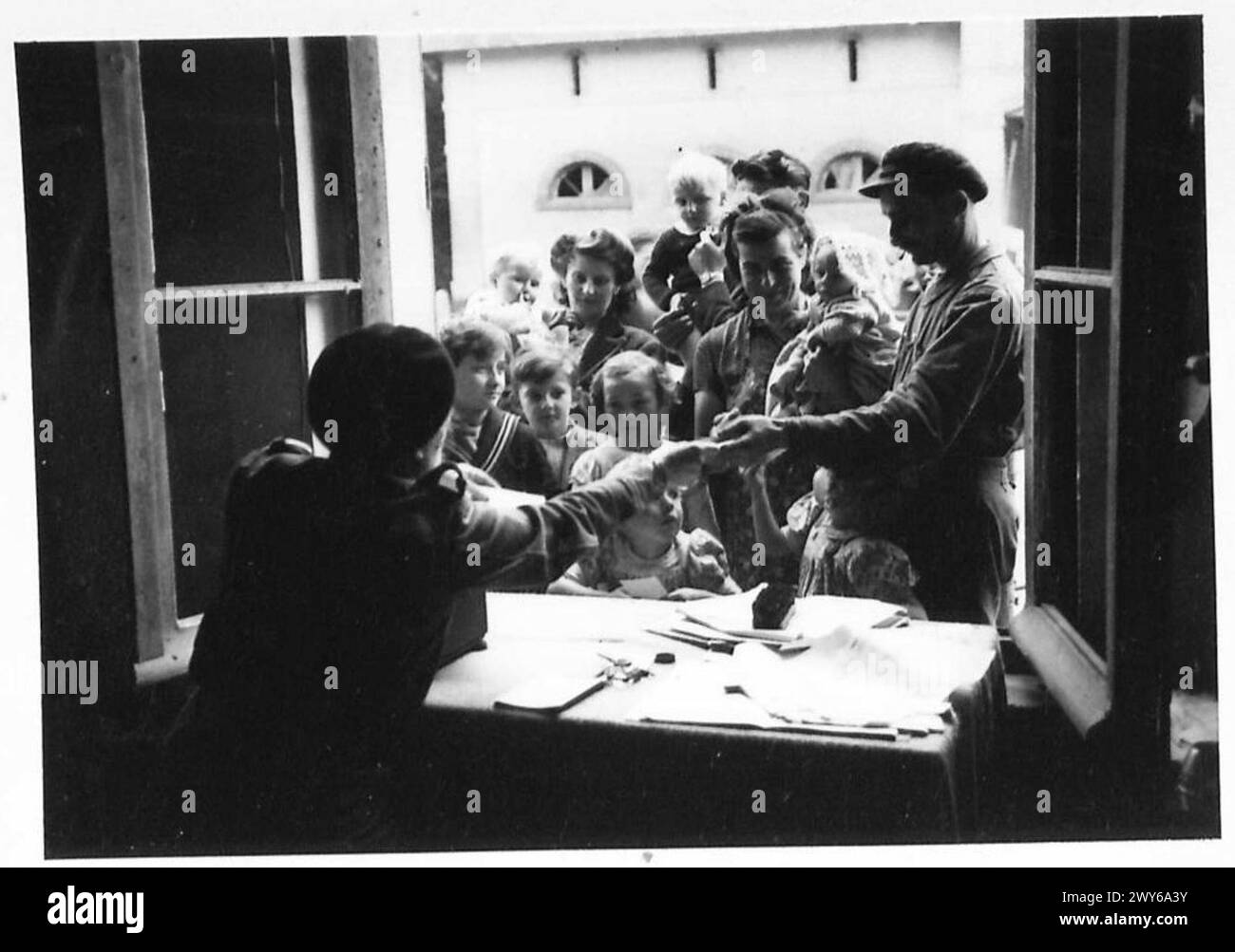 Ein französisches ATS-Mitglied verteilt Registrierungskarten an Flüchtlinge im Rahmen von Zeitungsdruckoperationen der British Army, 21st Army Group. Stockfoto