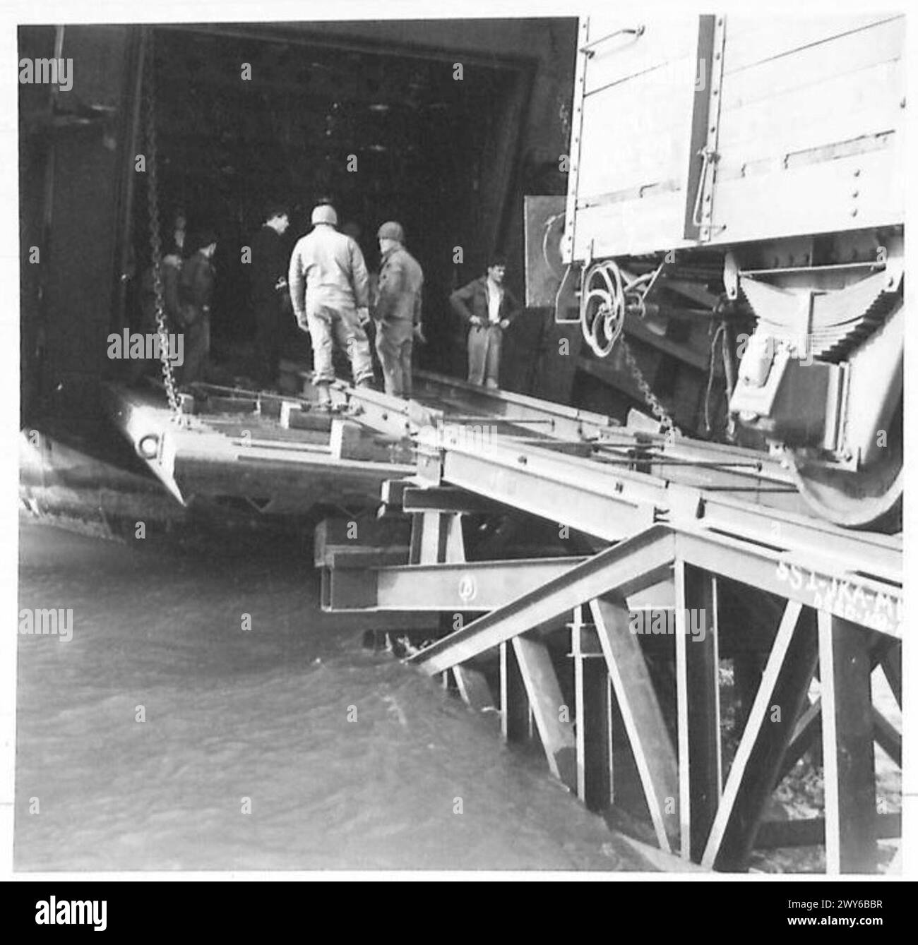 Ein Eisenbahnwaggon fährt von einem Landing Ship Tank ab und transportiert vorgefertigte Materialien für den Hafenbau unter der British Army 21st Army Group. Stockfoto
