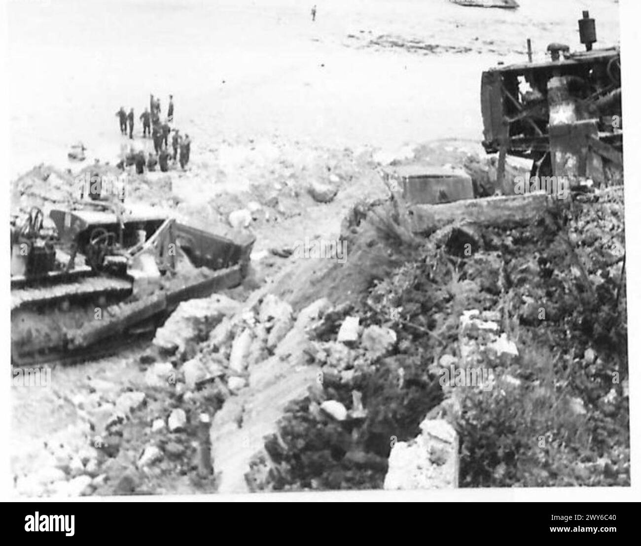 Bulldozer und Militärangehörige bereiten das Ufer und die Straße in einem vorgefertigten Hafen vor und dokumentieren die logistischen Operationen der britischen Armee, 21. Armeegruppe. Stockfoto