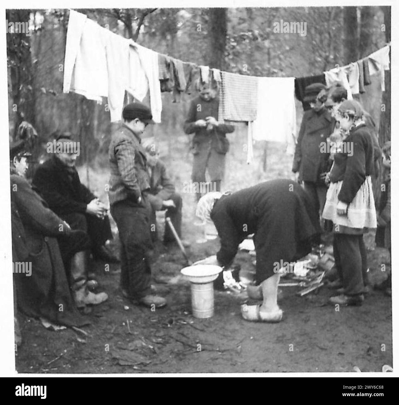 Eine Gruppe deutscher Zivilisten, darunter Flüchtlinge, versammelt sich um ein Feuer in der Nähe ihres Billet unter britischer Militärregierung. Stockfoto