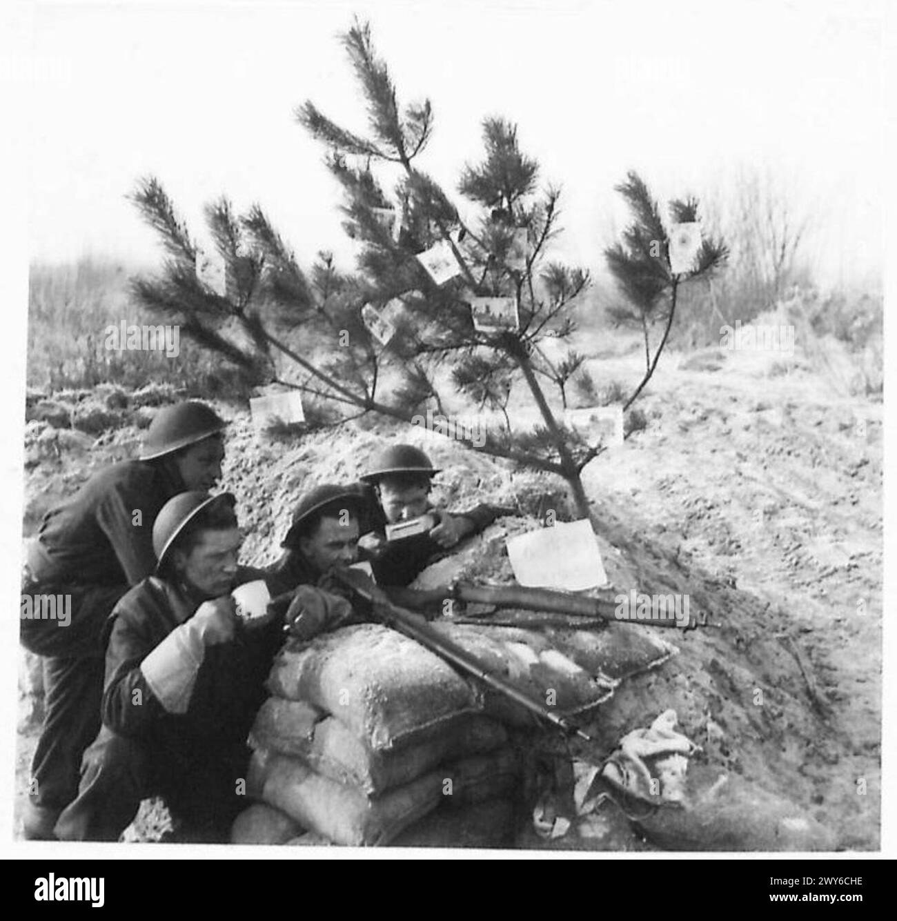 Vorwärtsgerichtete Truppen erhalten Tee und schmücken einen kleinen Weihnachtsbaum mit Karten von zu Hause, um Weihnachten auf dem Feld während des Zweiten Weltkriegs zu beobachten Stockfoto