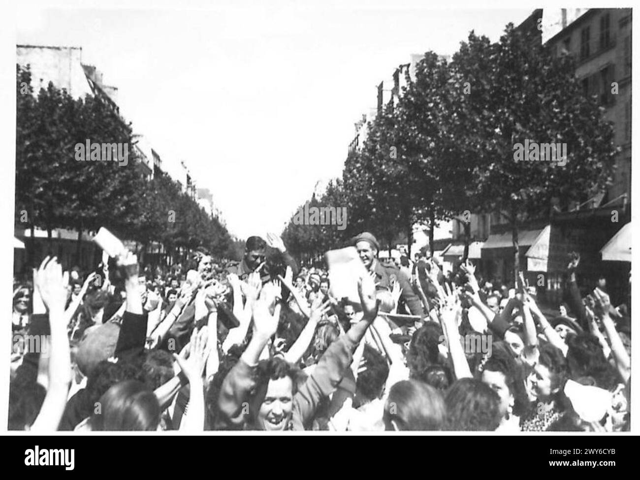 Die Leute von Paris drängen sich auf die Straßen, um britische, amerikanische, kanadische und französische Truppen zu begrüßen, die während des Zweiten Weltkriegs in die befreite Stadt einmarschieren Stockfoto