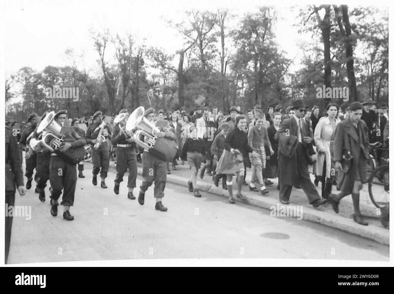 Britische Truppen der 7. Panzerdivision marschieren nach der Flaggenbrechzeremonie in Berlin weg, gefolgt von deutschen Zivilisten, die das Ereignis beobachten. Stockfoto