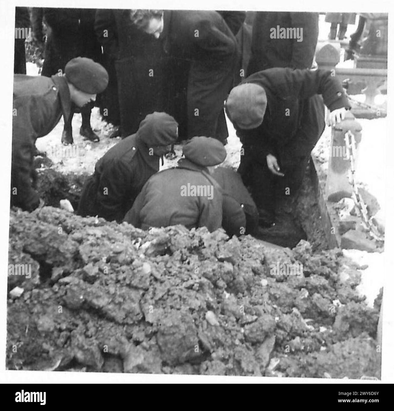 Opfer der Gräueltaten der Nazis werden auf einem Friedhof begraben, wobei trauernde Eltern anwesend sind, dokumentiert von der britischen Armee, 21. Armeegruppe. Stockfoto