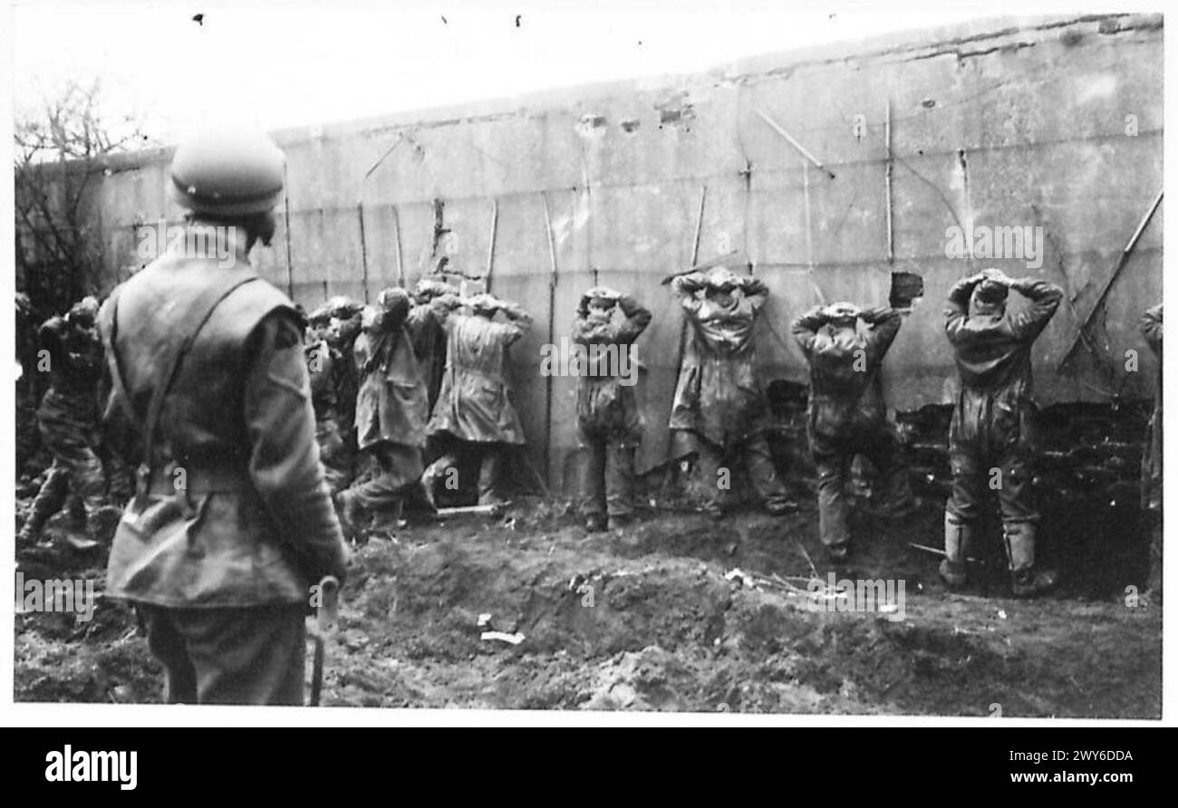 Die Gefangenen des Fallschirmregiments müssen mit erhobenen Händen gegen die Wand gerichtet sein, während die 3. Division in Richtung Kervenhiem vorrückt. Stockfoto