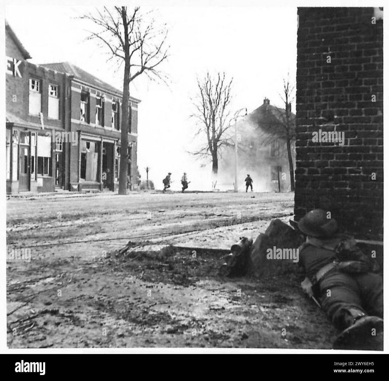 Der britische Infanteriezug überquert eine Straße unter feindlichem Feuer, indem er eine Rauchbombe benutzt, um einen Bildschirm zu erstellen und sich während der Kampfeinsätze auf ein Haus vorzustoßen. Stockfoto