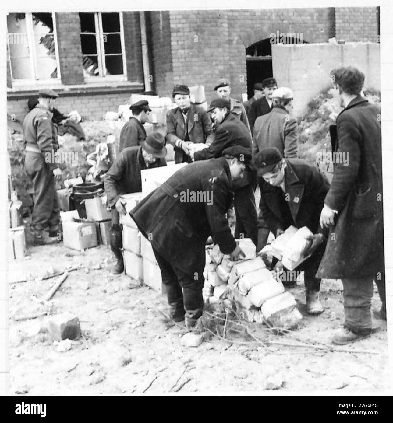 Britische Armeeangehörige unter der alliierten Militärregierung in Deutschland verteilen und stapeln deutsche Militärrationen, die von zurückziehenden Truppen hinterlassen wurden, als erste Mahlzeit, die Zivilisten zur Verfügung gestellt wurde. Stockfoto