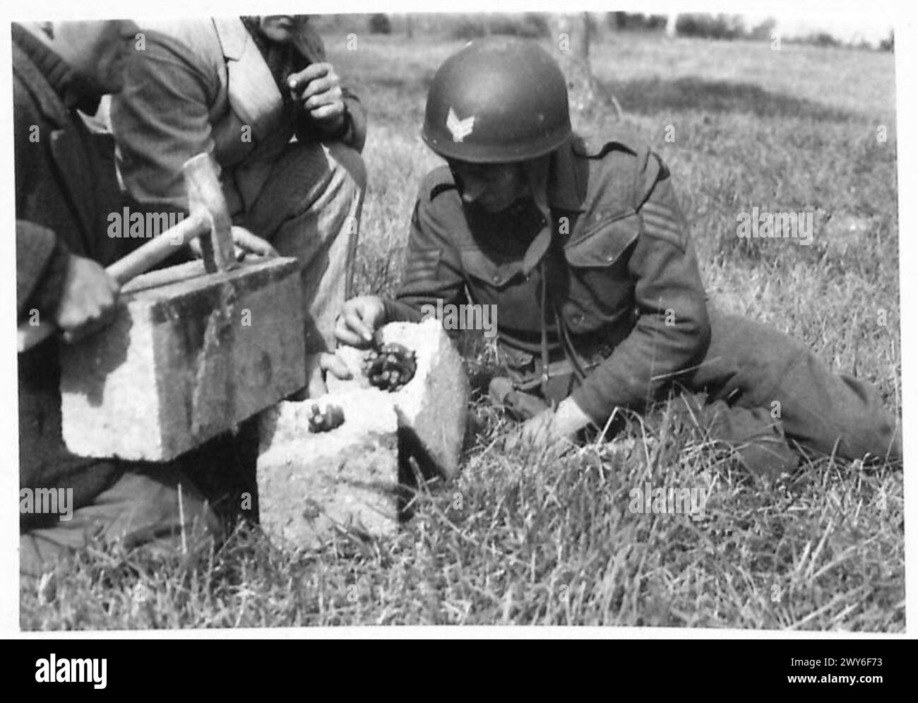 Ein Sergeant der 3. Division untersucht die Munition, die beim Bruch eines Pflastersteins entdeckt wurde, was die Aktivität der Widerstandsbewegung veranschaulicht. Stockfoto