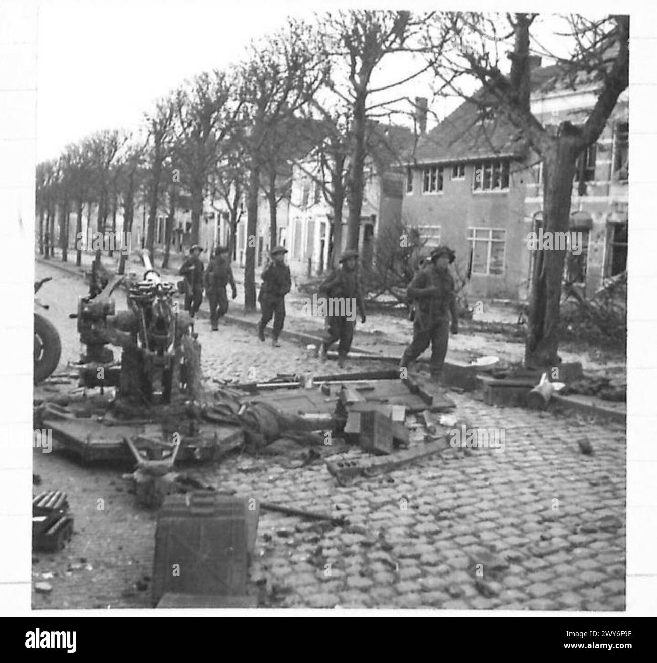 Truppen einer Kompanie, 4. Battalion Lincolns, dringen in eine niederländische Stadt nördlich von Mark, Holland, vor, vorbei an einer verlassenen deutschen Artillerie-Kanone. Stockfoto