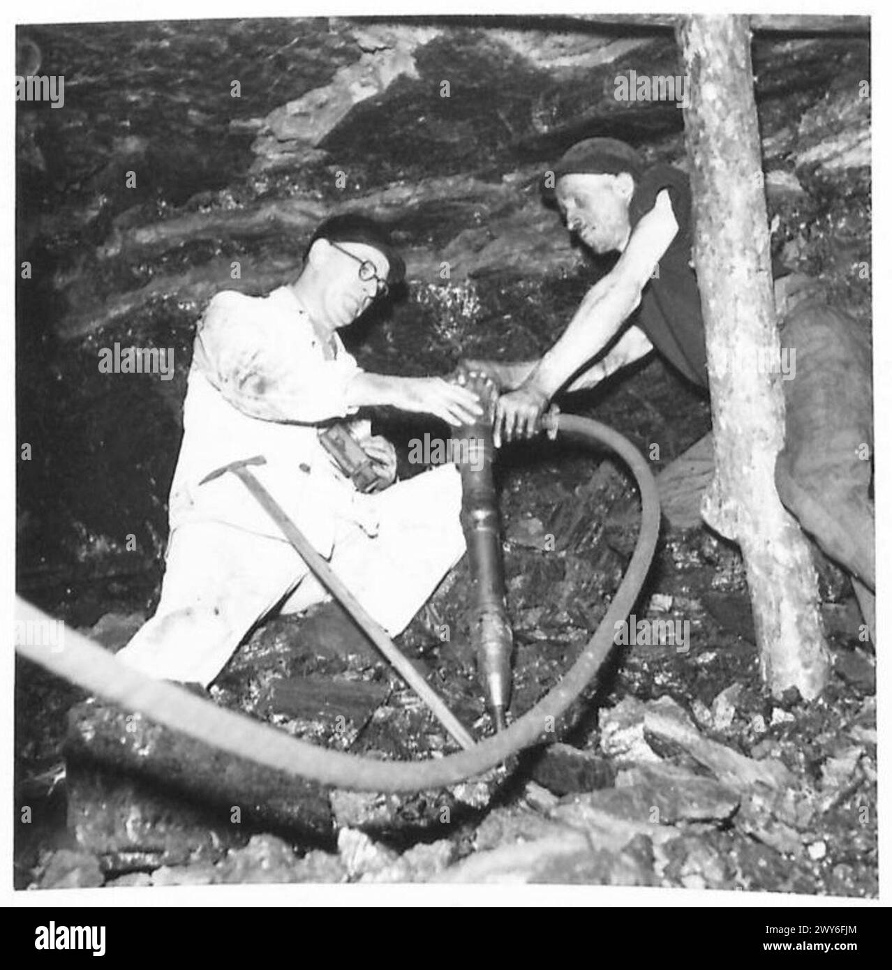Der zivile Bergbauexperte G.L. Williams spricht mit einem Bergmann, der eine Druckluftbohrmaschine im unteren Bereich der norddeutschen Kohlewand unter Aufsicht der britischen Rheinarmee betreibt. Stockfoto