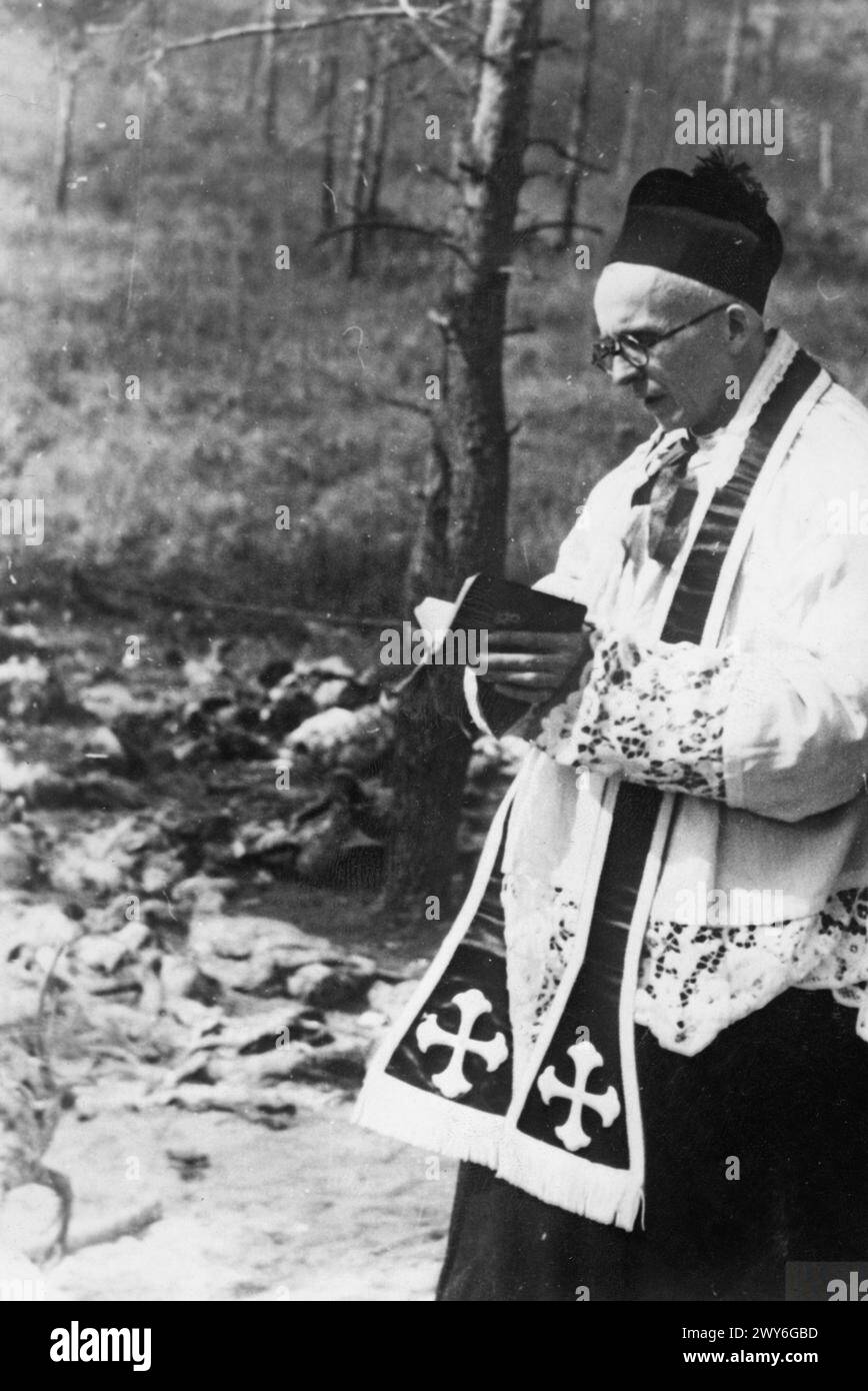 Reverend Stanisław Jasiński, ein polnischer Priester, betet über ein offenes Massengrab der Opfer des Massakers von Katyn im Jahr 1940. Stockfoto