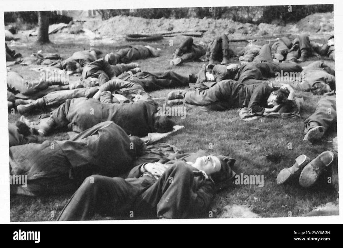Erschöpfte deutsche Gefangene ruhen sich aus, nachdem sie während der Rheinüberquerung der 2. Armee gefangen genommen wurden, beobachtet von der britischen Armee, 21. Armeegruppe. Stockfoto
