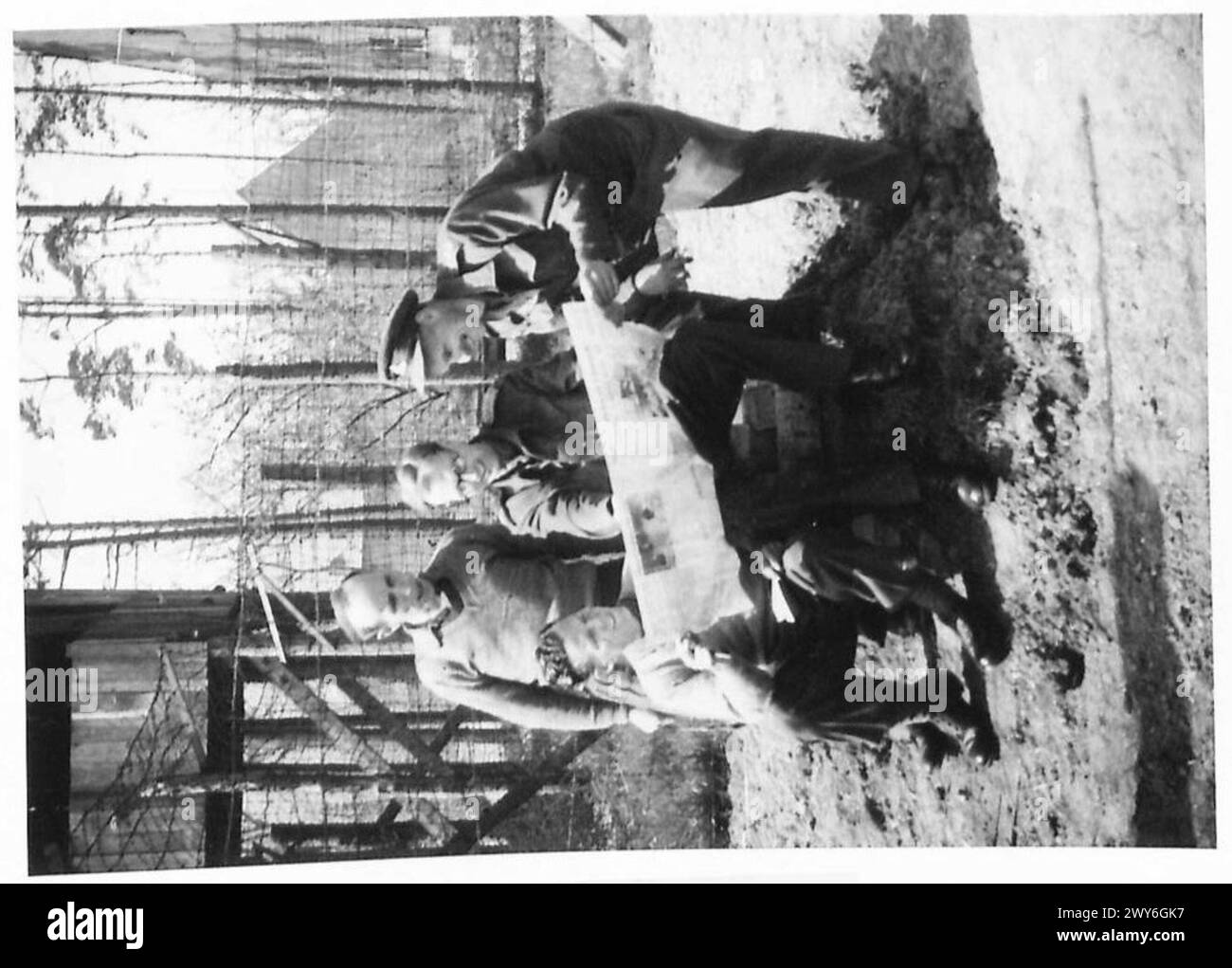 Am 12. April 1945 lasen britische Kriegsgefangene bei Oflag 79 in Deutschland am Tag der Befreiung eine britische Zeitung. Stockfoto