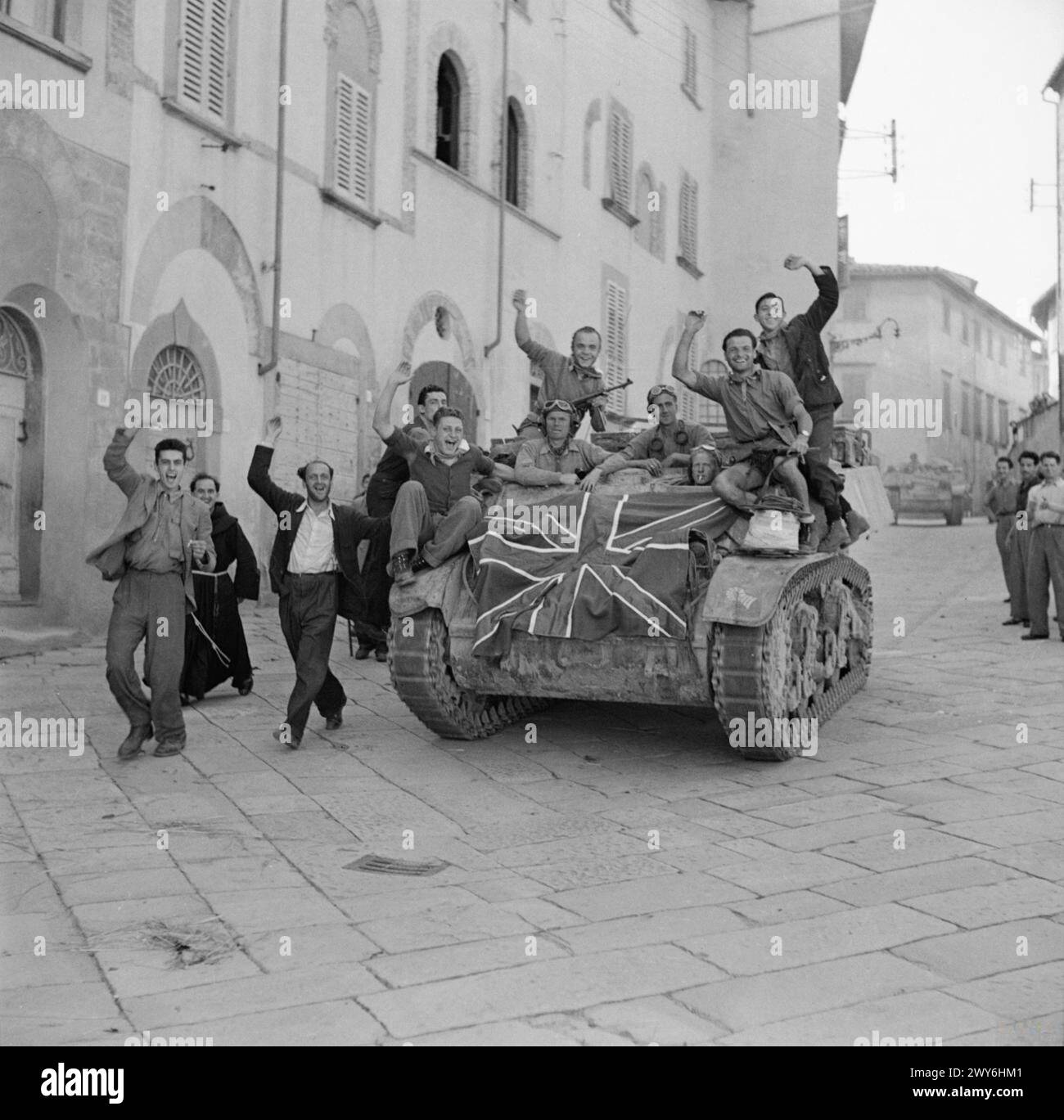 Italienische Zivilisten steigen an Bord eines turbulenten Stuart-Aufklärungspanzers, der mit einer Union Flag verziert ist, als die britische 8. Armee am 15. Juli 1944 während der Operationen des Zweiten Weltkriegs in Arezzo einmarschiert. Stockfoto