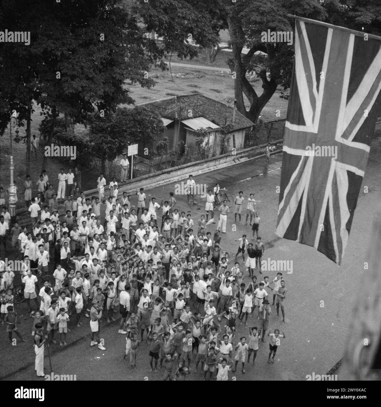 Eine britische Flagge fliegt über einer jubelnden Menge, als die 5. Indianerdivision 1945 in Singapur eintrifft und damit das Ende der japanischen Besatzung markiert. Stockfoto