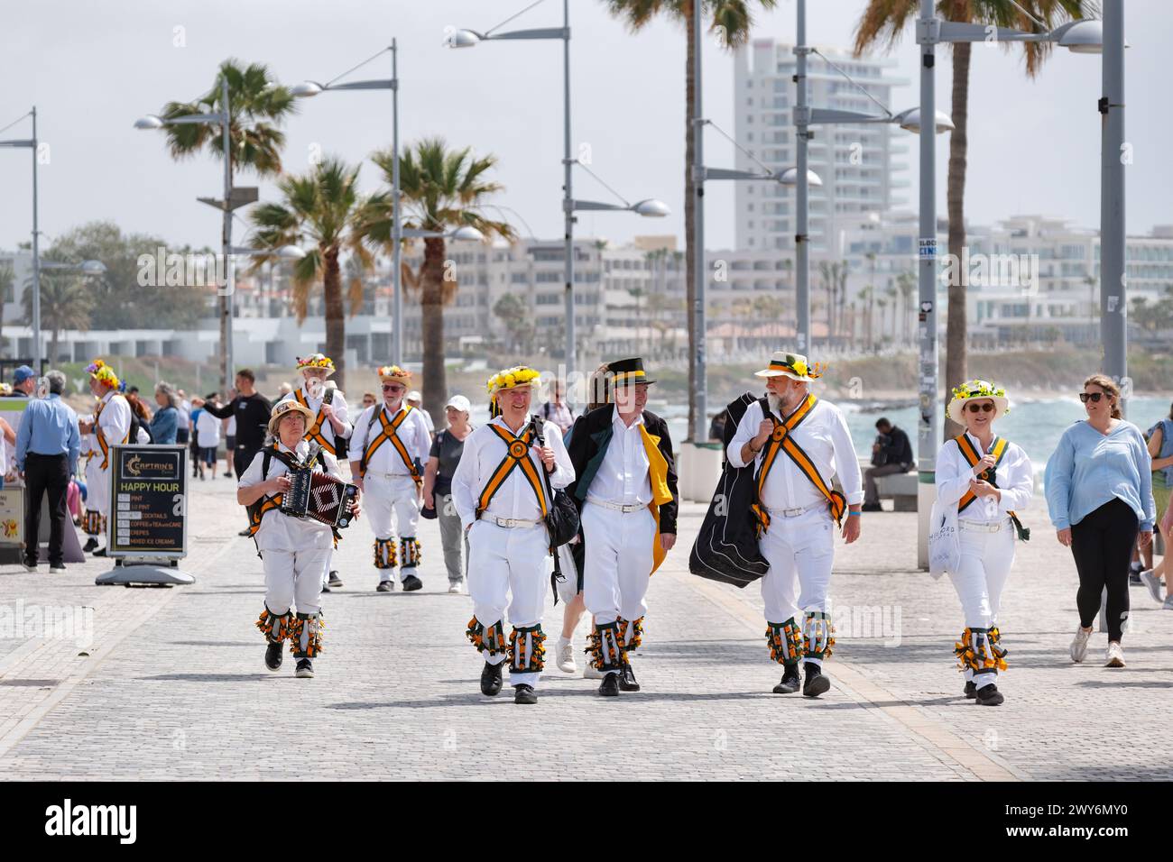 Eine Gruppe britischer morris-Männer, die durch den alten Hafen von Paphos, Zypern, spazieren gehen. Die Tänzer hatten gerade einen Tanz für die Öffentlichkeit vorgetragen Stockfoto