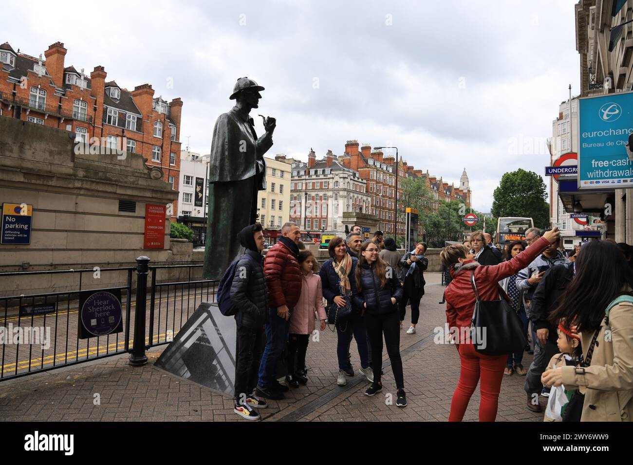 London, Großbritannien: Touristen posieren für ein Foto in der Nähe der berühmten Sherlock Holmes-Statue an der U-Bahn-Station Baker Street in London Stockfoto