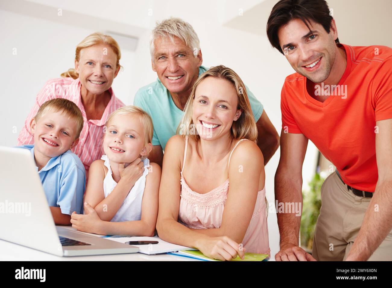 Glücklich, Eltern und Großeltern in der Lounge auf Laptop mit Kindern zur Unterhaltung zu Hause zur Entwicklung. Mom, Dad und Geschwister, die sich im Urlaub verbünden Stockfoto