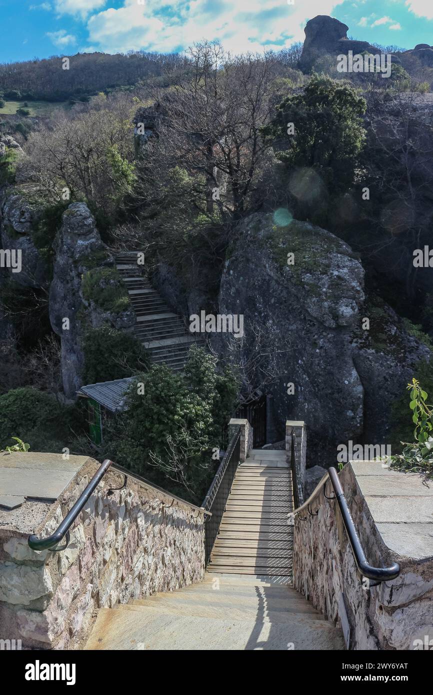 Begeben Sie sich auf eine magische Reise, während Sie eine bezaubernde Treppe hinaufsteigen, eingebettet in die atemberaubende Natur rund um die alten Kirchen von Meteora Stockfoto
