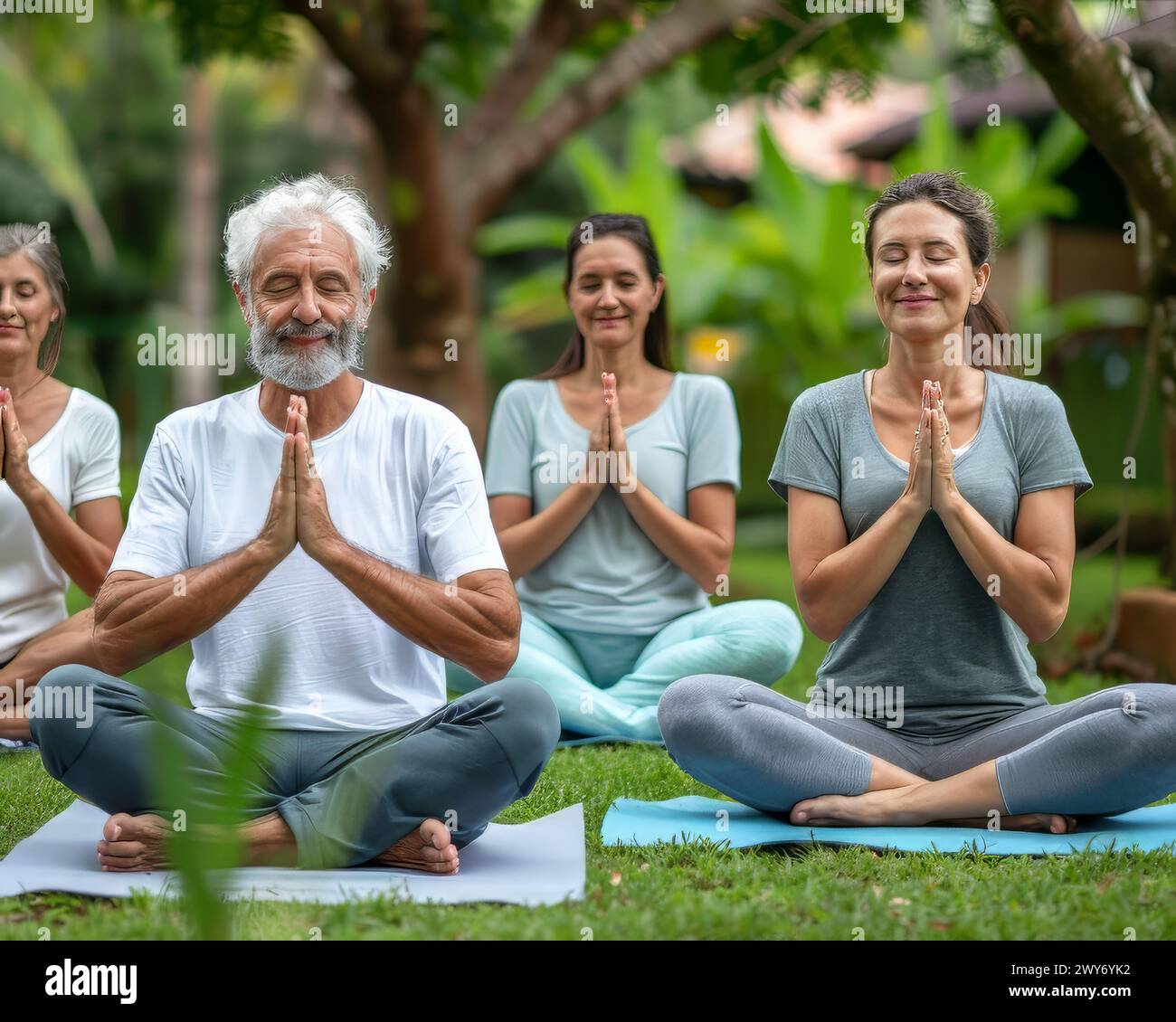 Eine Gruppe von Menschen sitzt auf dem Gras und meditiert Stockfoto
