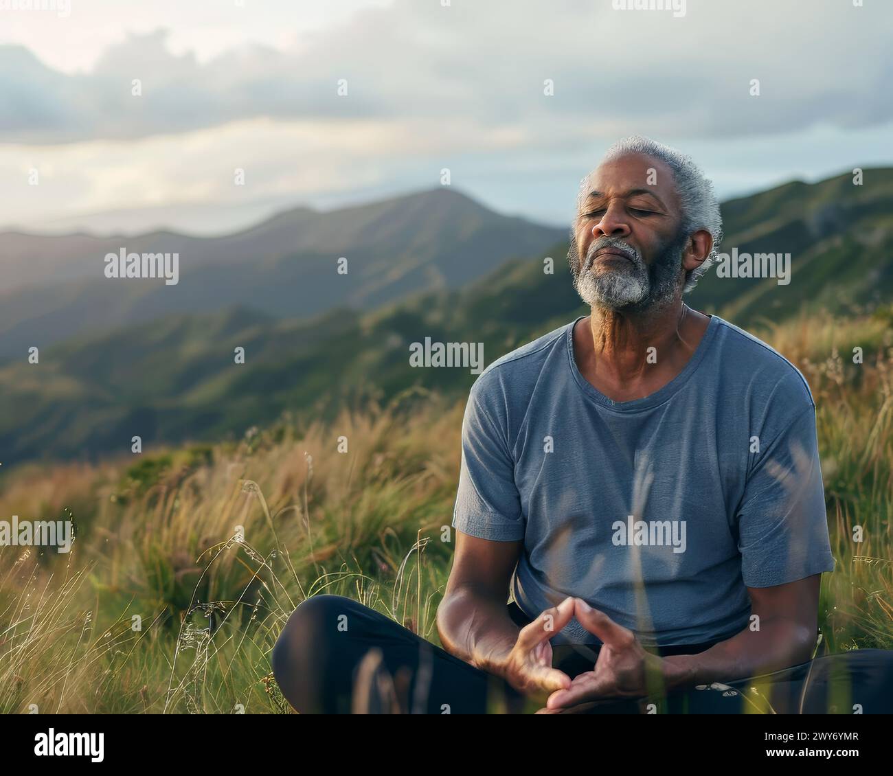 Ein Mann sitzt auf einem Feld und blickt in den Himmel. Er trägt ein blaues Hemd und ist in friedlicher und besinnlicher Stimmung Stockfoto