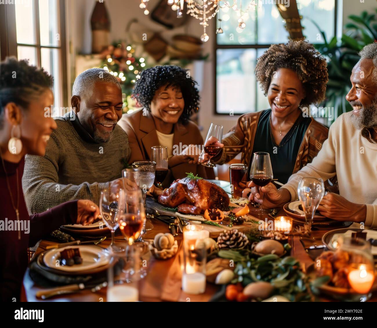 Eine Familie versammelt sich um einen Tisch mit einem truthahn und Weingläsern. Sie lächeln und genießen die Gesellschaft des anderen Stockfoto