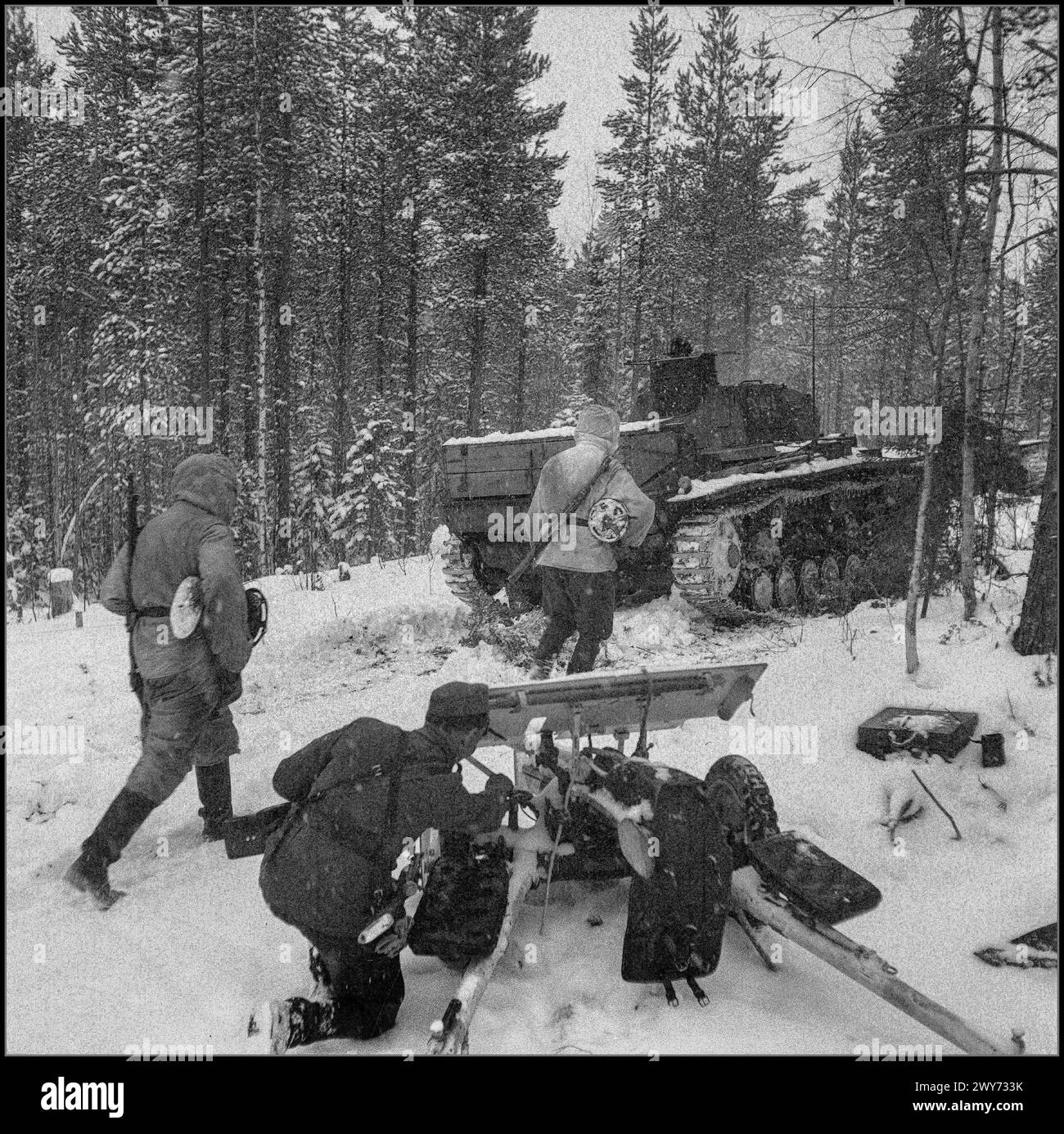 Deutsche und finnische Einheiten 1942, begleitet von einem Panzer PzKpfw III Ausf B, forschen auf einer winterlich verschneiten Forststraße in Richtung Kestenga Karelien UdSSR vor. Im Vordergrund steht ein finnischer Artilleriesoldat mit einer 37-mm-Panzerabwehrkanone des schwedischen Designs „Bofors“ (37 PstK/36 Bofors). Stockfoto