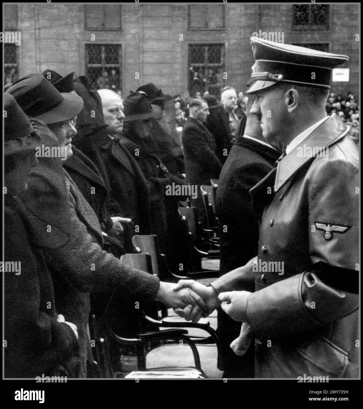 Adolf Hitler mit schwarzem Armband spricht den Familien der bei der Explosion im Münchner Bürgerbräukeller Getöteten sein Beileid aus. 1939 Nazi-Deutschland. Johann Georg Elser 4. Januar 1903 – 9. April 1945) war ein deutscher Arbeiter, der am 8. November 1939 einen aufwändigen Mordanschlag auf Adolf Hitler und andere hochrangige Nazi-Führer auf dem Bürgerbräukeller in München plante und durchführte. Elser baute und platzierte eine Bombe in der Nähe des Bahnsteigs, von dem Hitler eine Rede halten sollte. Es hat Hitler nicht getötet Stockfoto