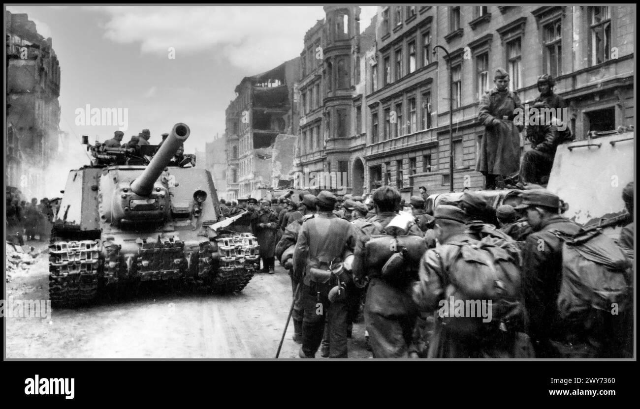 Berlin Nazi-Kapitulation 1945 WW2 Eine Kolonne deutscher Kriegsgefangener passiert durch sowjetische Selbstfahrlafetten ISU-122 entlang der Straße von Berlin Nazi-Deutschland Zweiten Weltkrieg die ISU-122 wurde als mächtiges Angriffsgewehr, selbstfahrende Haubitze und Langstreckenpanzerzerstörer eingesetzt. Stockfoto