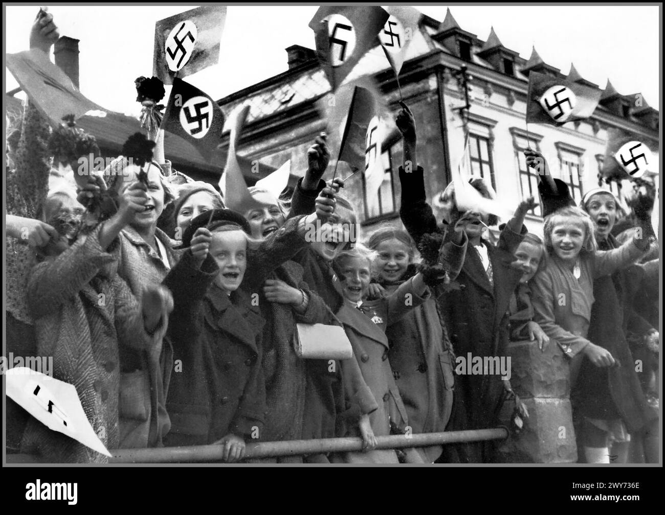 1938 Nazi-Propagandabild junger deutscher Kinder aus der tschechoslowakischen Stadt Trautenau (Trautenau ist der deutsche Name, Tschechoslowakisch ist Trutnov) grüßen die ankommenden Besatzungstruppen der Nazi-Wehrmacht. Trautenau Tschechoslowakei. Die militärische Besetzung der Tschechoslowakei durch Nazi-Deutschland begann 1938 mit der deutschen Annexion des Sudetenlandes, setzte sich mit der Schaffung des Protektorats Böhmen und Mähren fort und erstreckte sich bis Ende 1944 auf alle Teile der Tschechoslowakei Stockfoto