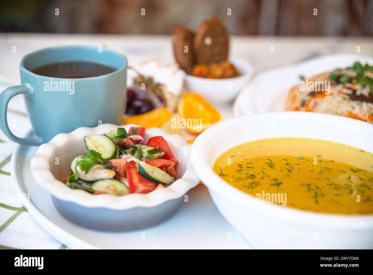 Usbekische Nationalgerichte, Plov, Shurpa, Salat und nicht auf einem Tablett mit Tee. Traditionelle usbekische Küche. Hintergrund mit kariertem Tischtuch. Stockfoto