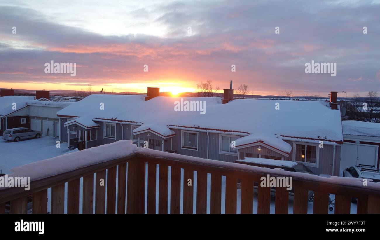 Sonnenaufgang in einer kleinen verschneiten Stadt im Norden Schwedens. Die Sonne geht über den Dächern auf. Stockfoto