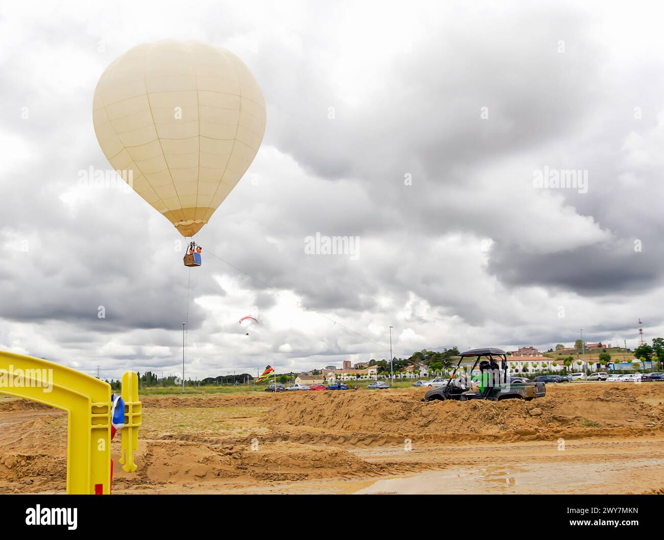 Heißluftballon fliegt am Himmel über die Landschaft während einer Freizeitveranstaltung mit vier mal vier und Paramotor. Stockfoto