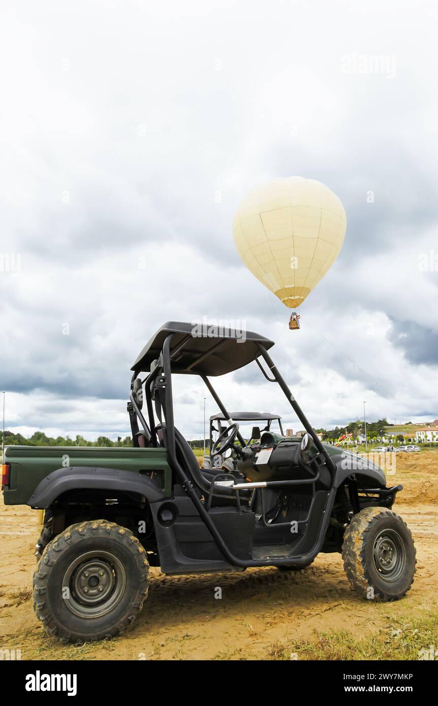 Heißluftballon fliegt über einem vier mal vier Auto, das auf dem Feldgelände steht. Stockfoto