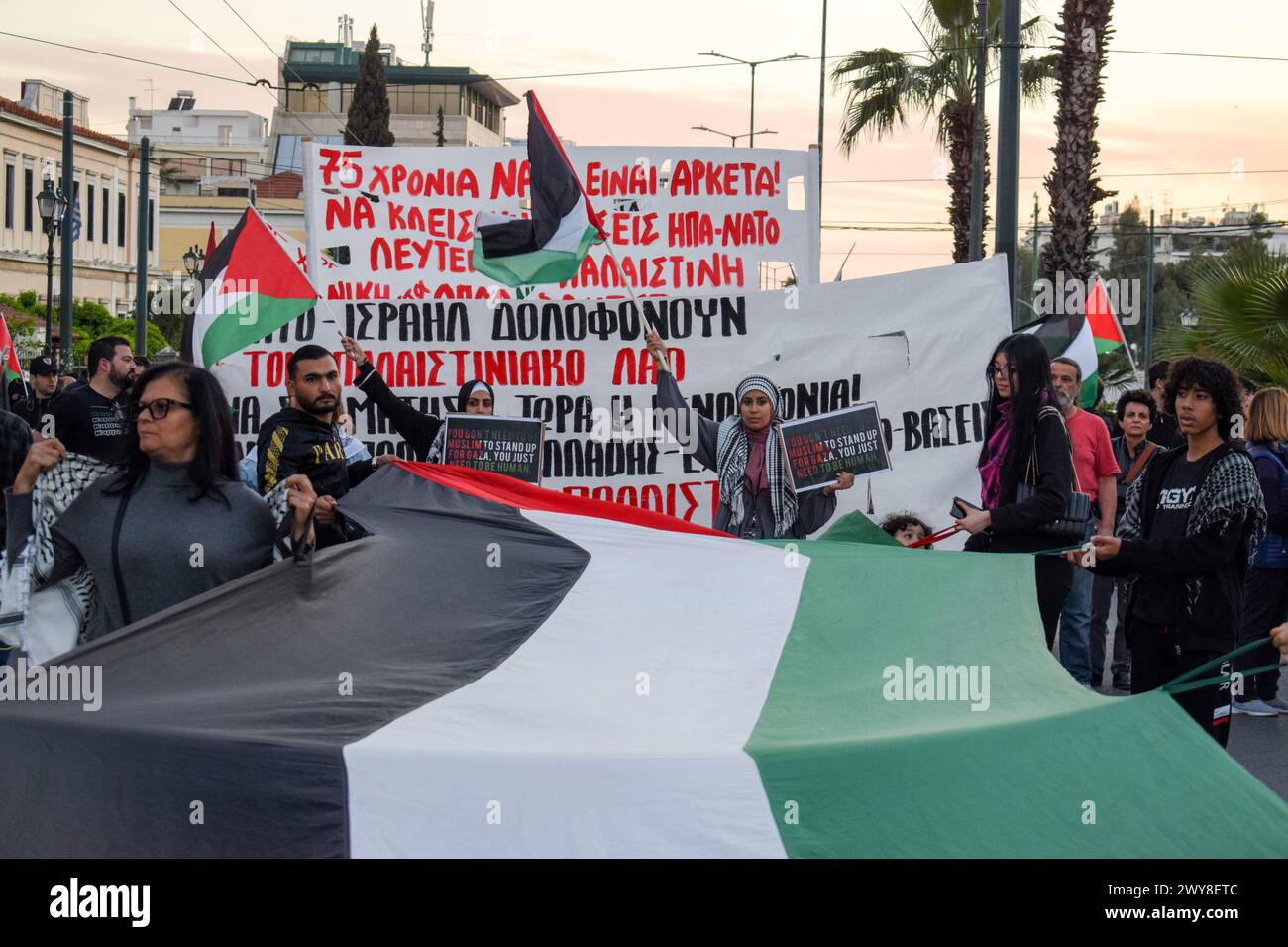 Athen, Griechenland. April 2024. Demonstranten marschieren mit einer riesigen palästinensischen Flagge während eines Protestes gegen die NATO. Die Außenminister trafen sich heute im NATO-Hauptquartier in Brüssel, um den 75. Jahrestag seit der Unterzeichnung des Gründungsdokuments der Allianz, des Nordatlantikvertrags, zu begehen. Quelle: Dimitris Aspiotis/Alamy Live News Stockfoto