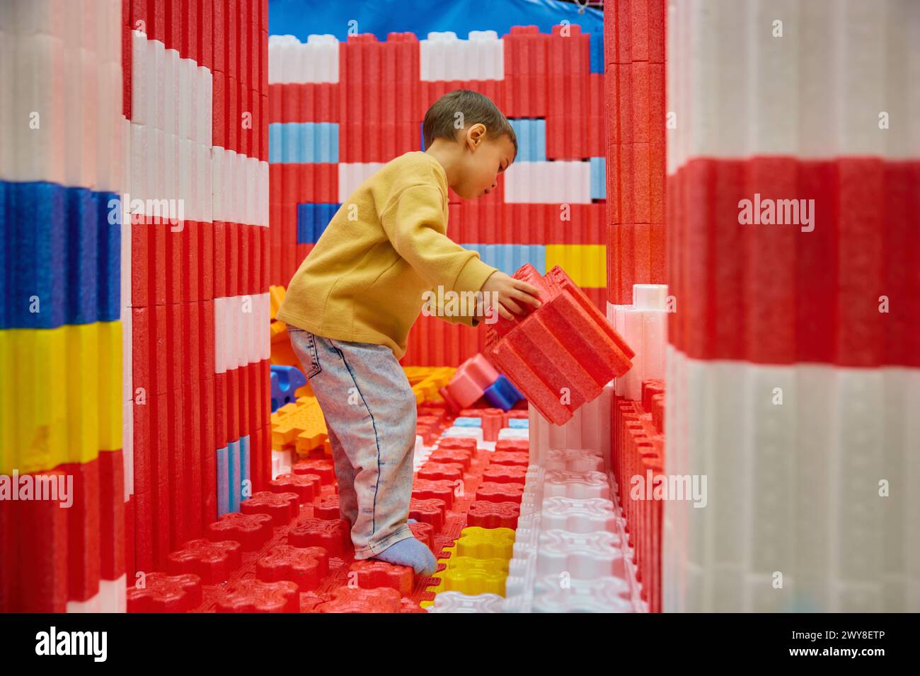 Kleiner Junge, der mit riesigen Bausteinen im Unterhaltungszentrum spielt Stockfoto