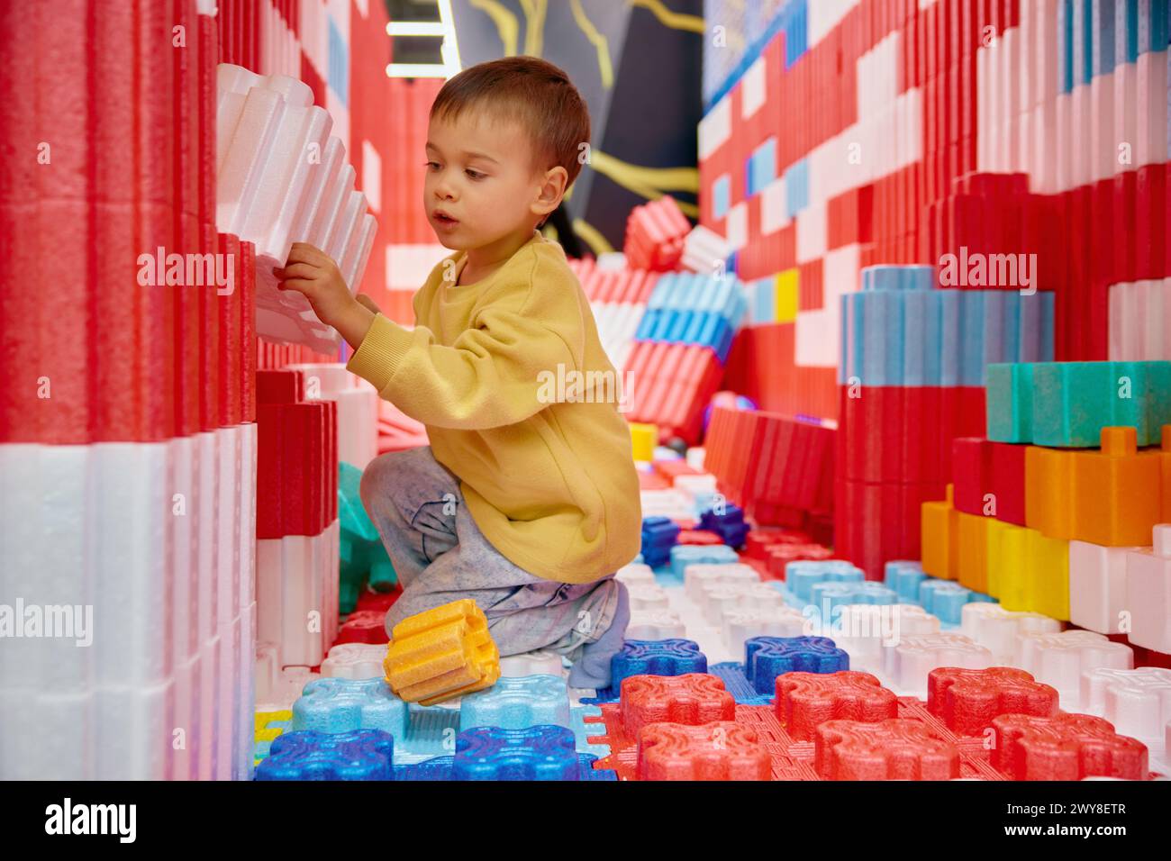 Junge Kind, das mit riesigen Bausteinen im Unterhaltungszentrum spielt Stockfoto