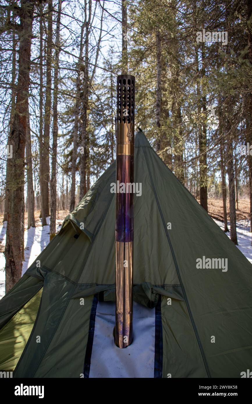 Dieses Bild zeigt ein Tipi-Zelt in einer verschneiten Landschaft, mit einem Metallschornstein, der aus dem Zelt ragt, was auf einen gemütlichen Campingplatz während des Sieges hindeutet Stockfoto